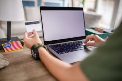 Military retiree looking at back of credit card near laptop